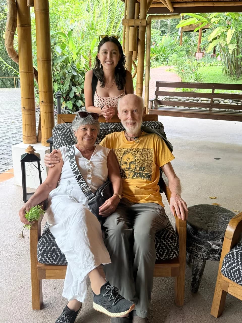 Tres personas sonriendo en una terraza de bambú rodeada de vegetación tropical